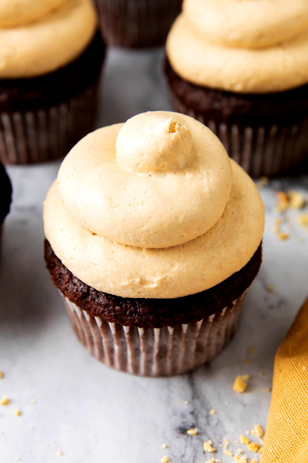 Fluffy, creamy, and smooth peanut butter frosting recipe for chocolate cake is piped onto a cupcake.
