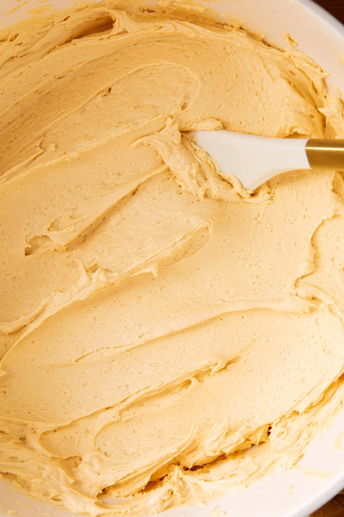 Close up of peanut butter frosting recipe in a mixing bowl to show smooth, thick and fluffy texture.