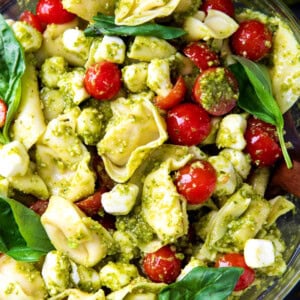 Serving bowl with pesto tortellini pasta salad with cheese tortellini, cherry tomatoes, and mozzarella pearls