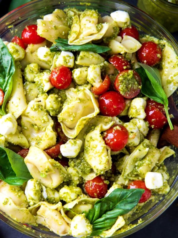 Serving bowl with pesto tortellini pasta salad with cheese tortellini, cherry tomatoes, and mozzarella pearls