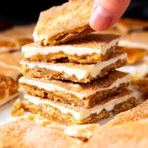 Someone grabbing a piece os this churro crack recipe from a stack