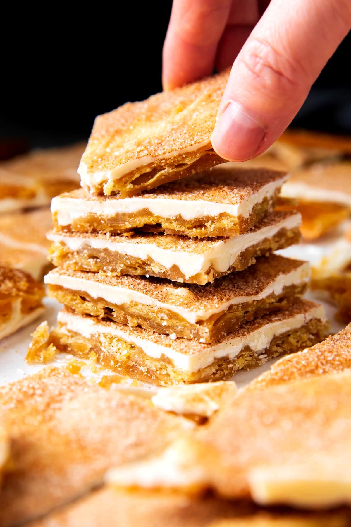 Someone grabbing a piece os this churro crack recipe from a stack.