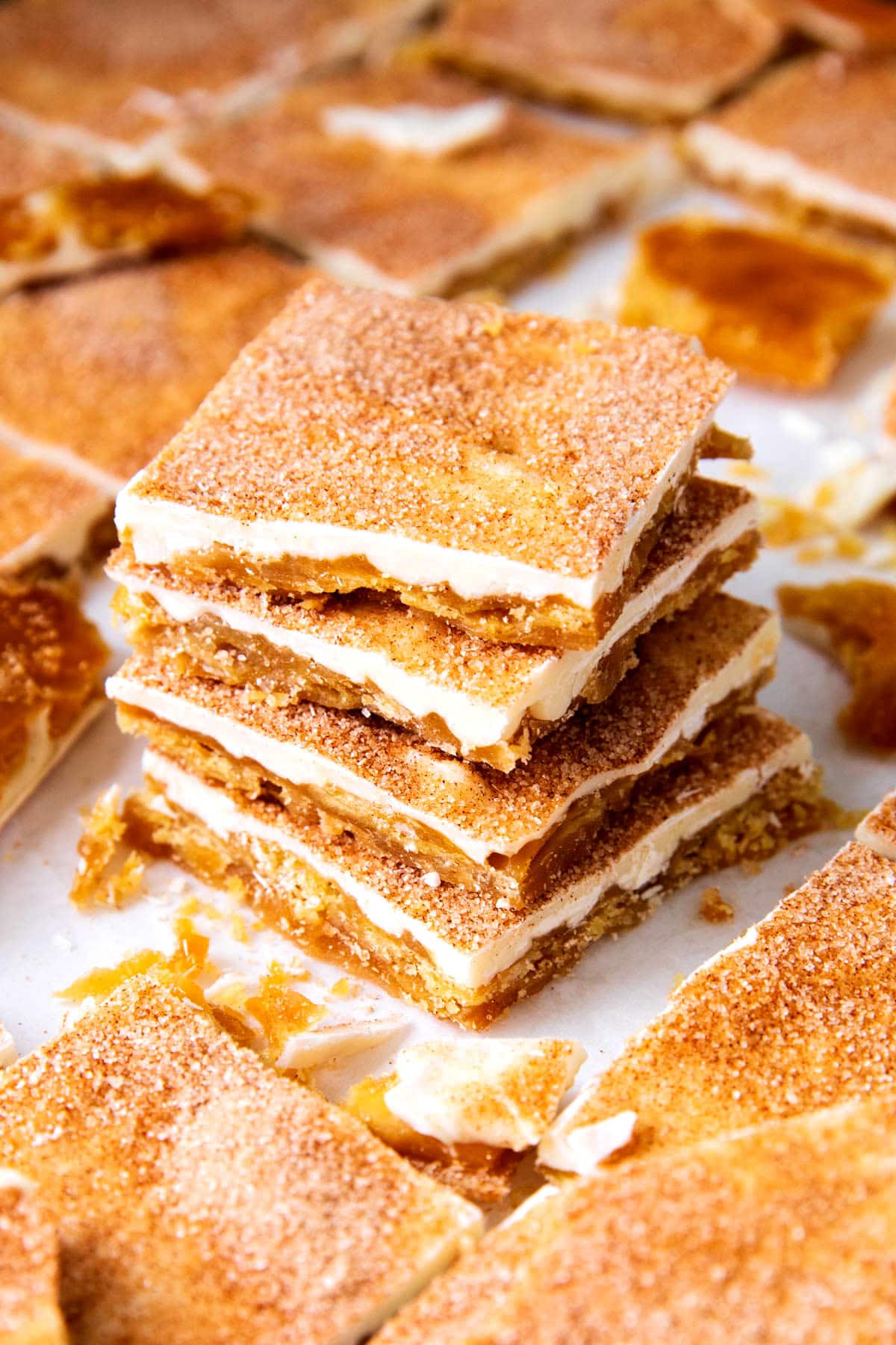 A stack of churro cracker candy shows crunchy layers of brown sugar candy, chocolate, and churro flavored topping.