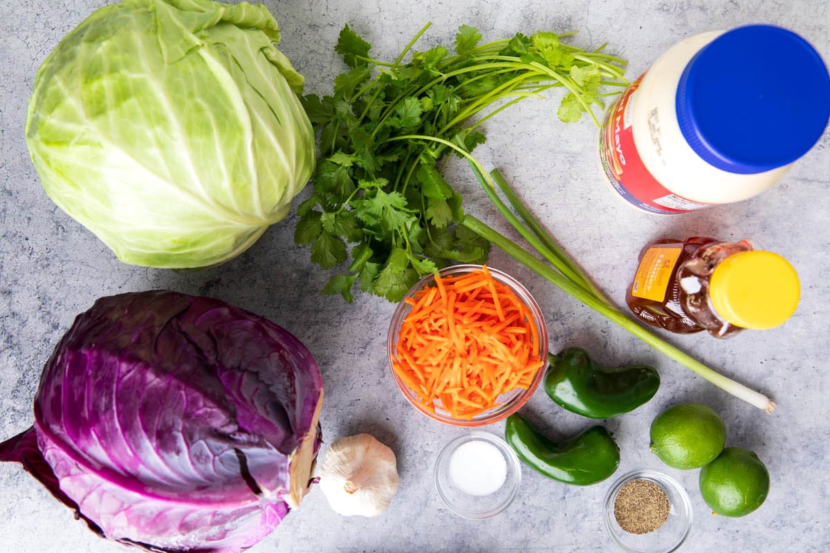 Creamy cilantro lime slaw ingredients include red and green cabbage, mayonnaise, carrots, fresh cilantro, honey, lime, and seasonings