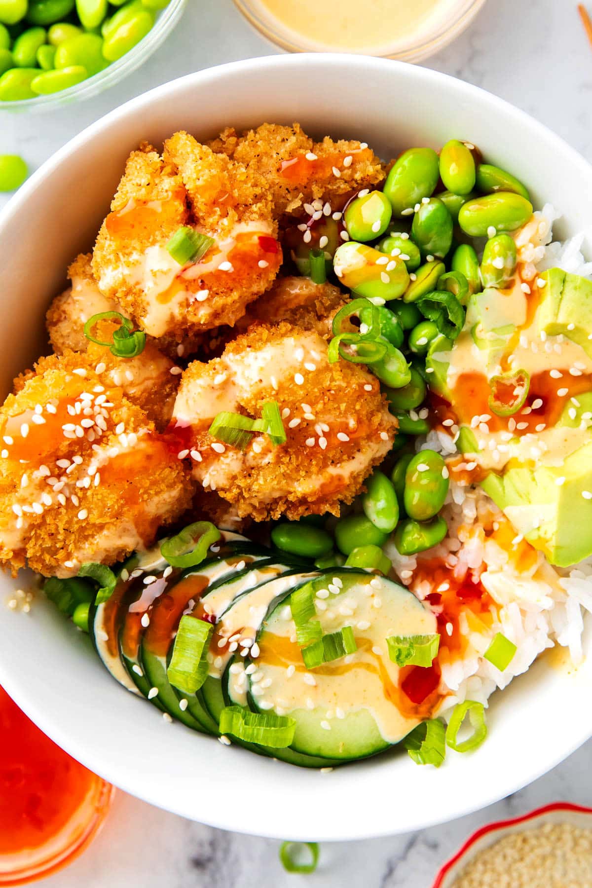 This Asian shrimp bowl feature crispy fried shrimp, edamame, avocado, yum yum sauce, and Thai sweet chili.