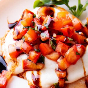 close up of easy bruschetta chicken shows juicy tomato and balsamic based topping over melted mozzarella