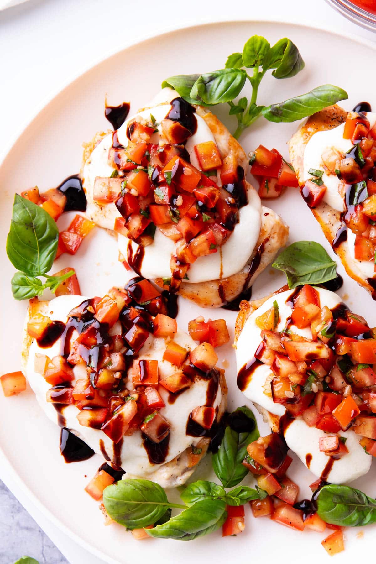Balsamic glaze is drizzled over this easy bruschetta chicken loads with tomato and garlic bruschetta topping.