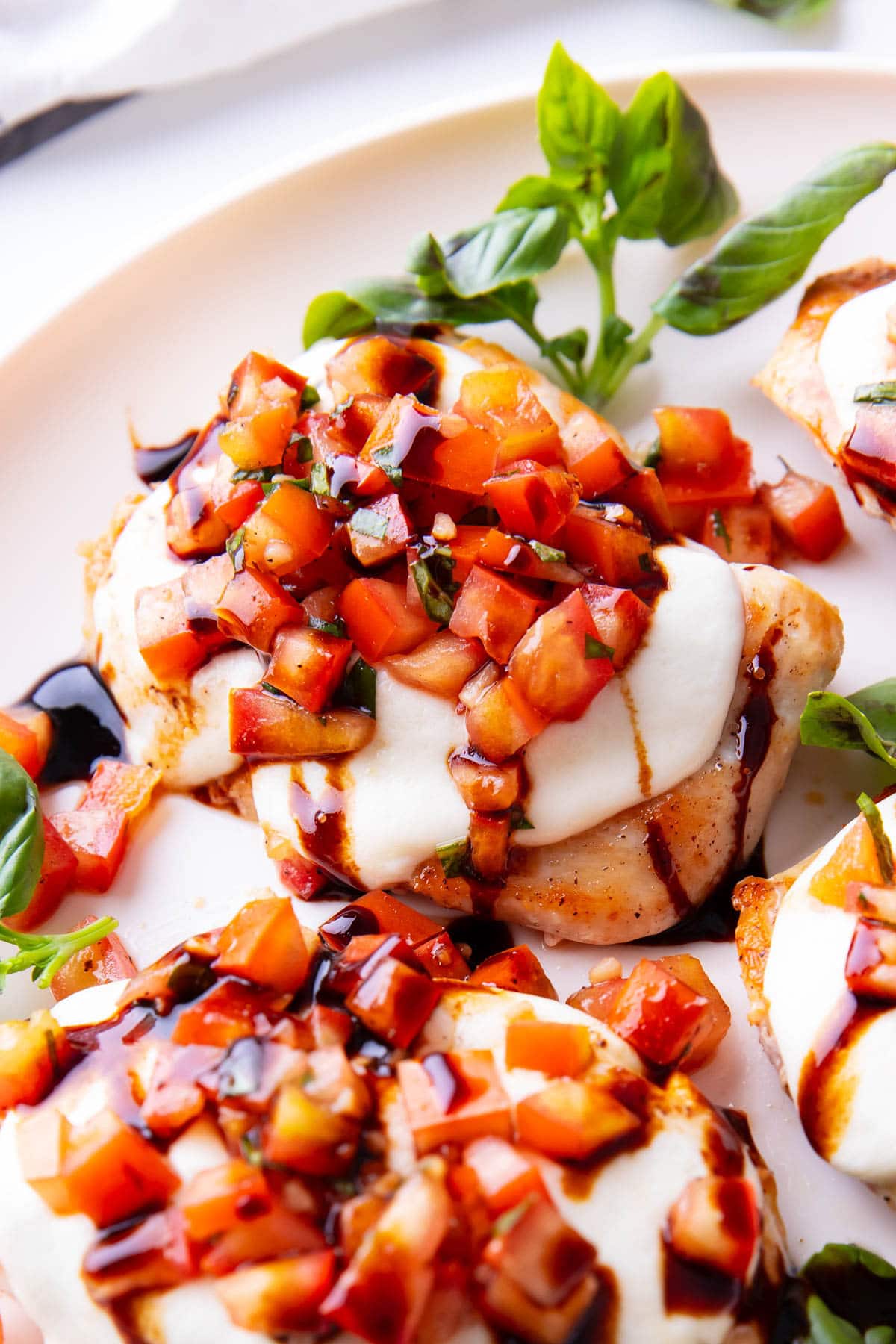 Basil and tomato bruschetta on chicken with balsamic glaze on top for an easy chicken dinner recipe.