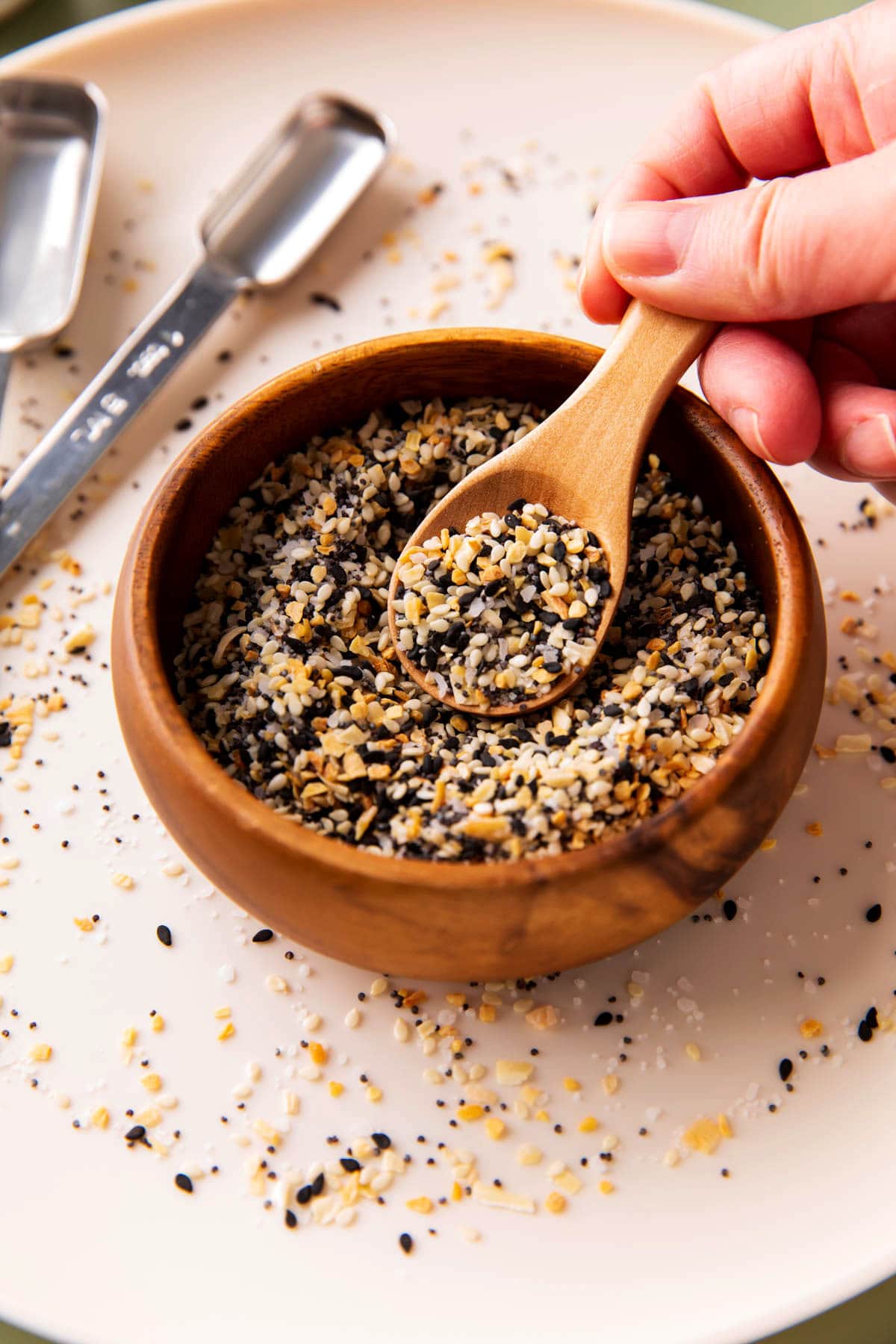 Someone spooning this homemade DIY everything bagel seasoning out of a spice bowl.