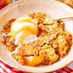 Apple Dump Cake served warm in a bowl with caramel drizzle and vanilla ice cream