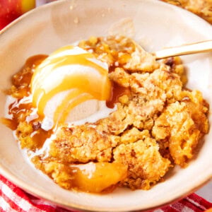 Apple Dump Cake served warm in a bowl with caramel drizzle and vanilla ice cream