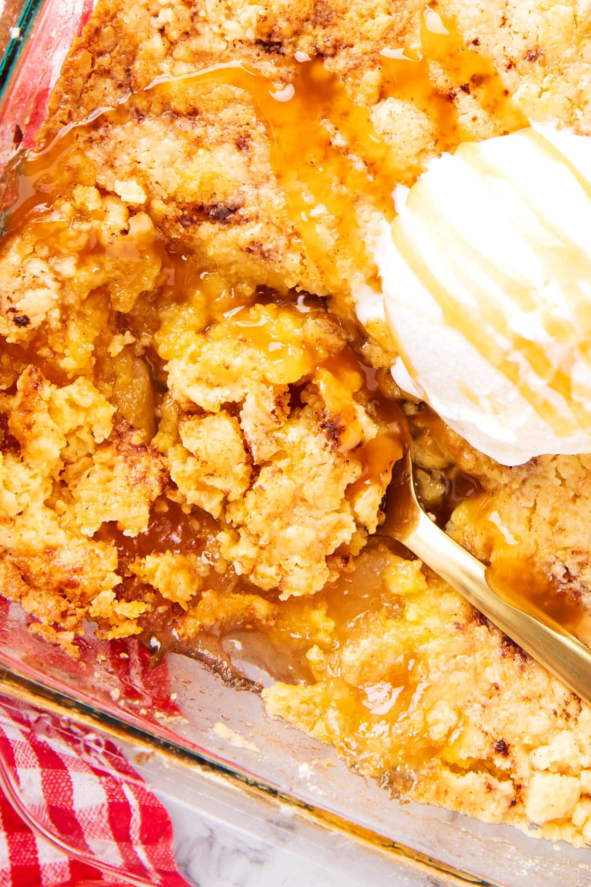A spoon scoops out apple pie filling and apple crumb topping in a dish of Apple Dump Cake.