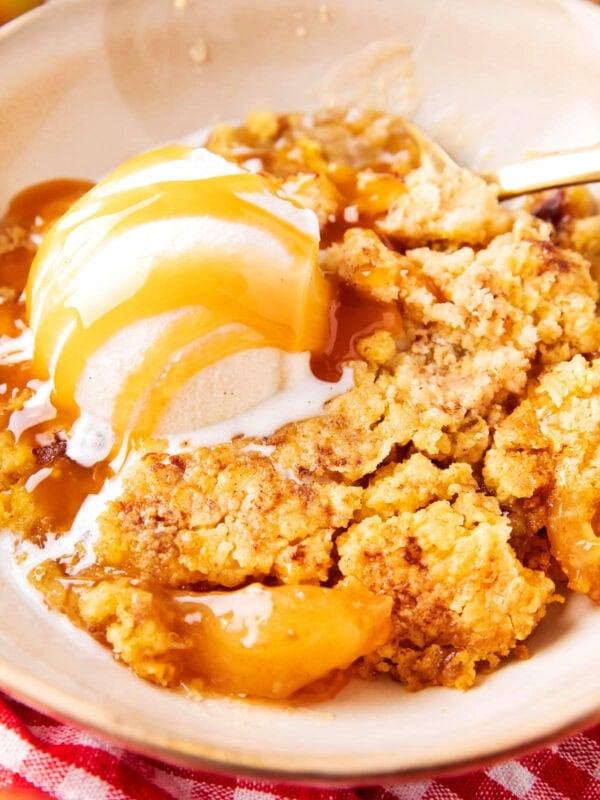Apple Dump Cake served warm in a bowl with caramel drizzle and vanilla ice cream