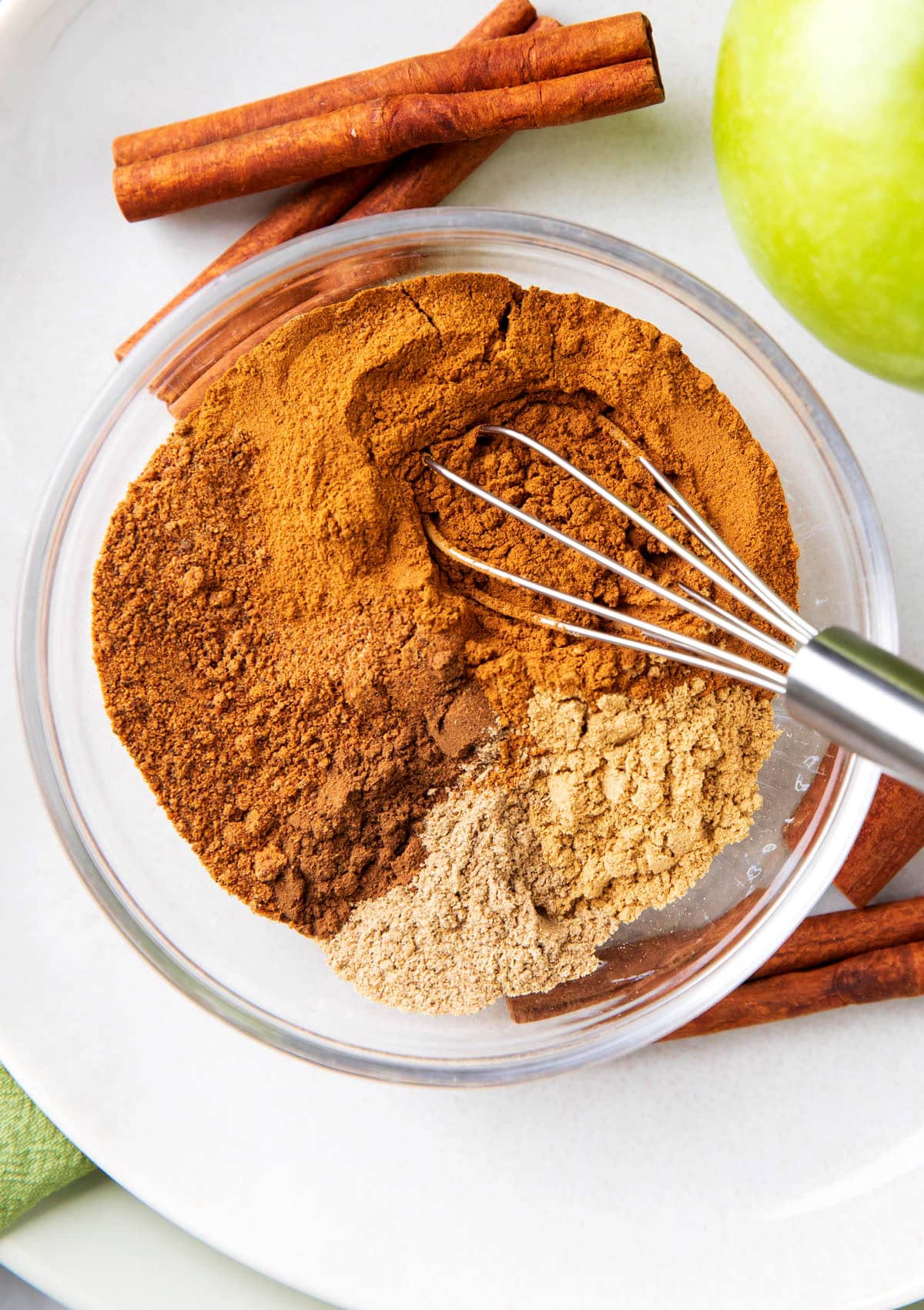 Close up of Apple Pie Spice ingredients including ground cinnamon, nutmeg, allspice, cardamom, and ginger.