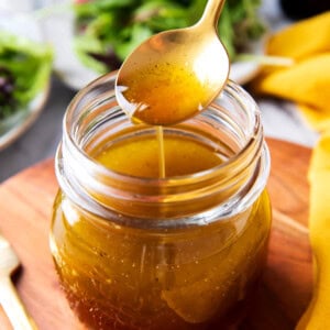 Close up of someone holding a spoonful of Maple Vinaigrette dribbling it down into a salad dressing jar