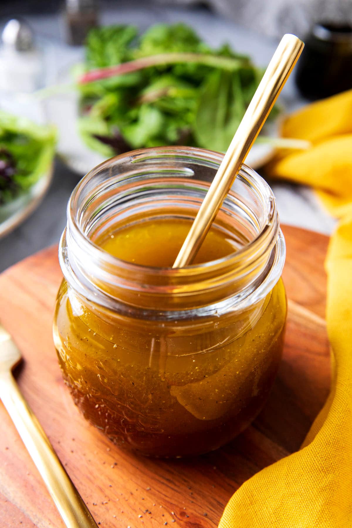 A jar of this homemade salad dressing recipe with dijon and maple syrup shows flavorful olive oil, pure maple syrup, and a touch of apple cider vinegar for a tangy sweet dressing.