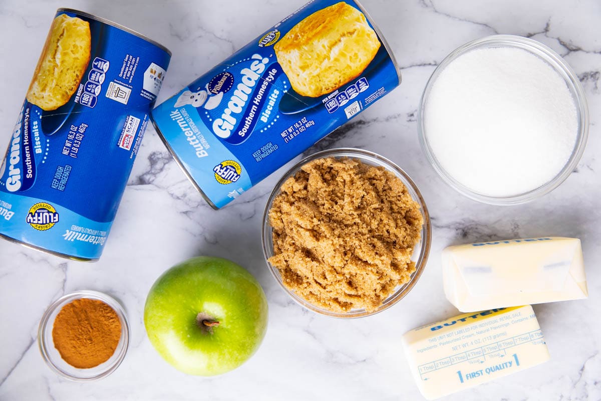Apple Monkey Bread ingredients including sugar, ground cinnamon, green apple, buttermilk biscuits, butter and brown sugar.