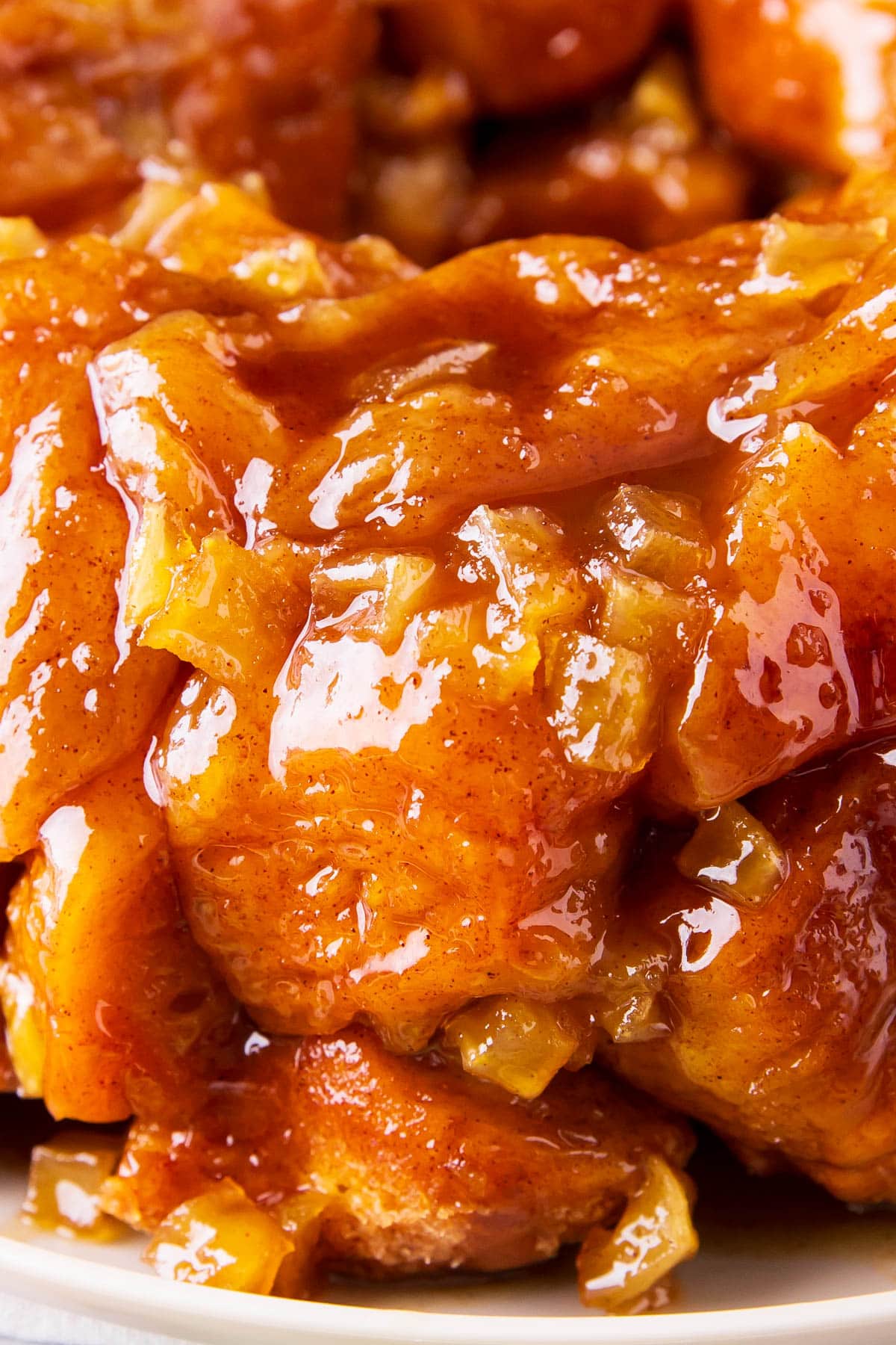 Close up of this cinnamon fritter baked good shows buttery brown sugar glaze coating soft bread pieces.