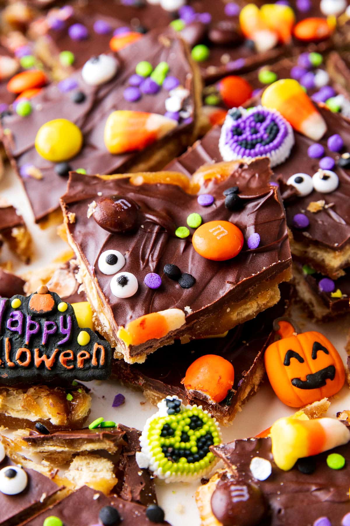 A piece of Halloween Crack that has spooky sprinkles, googly eyes, and candy corn on top.
