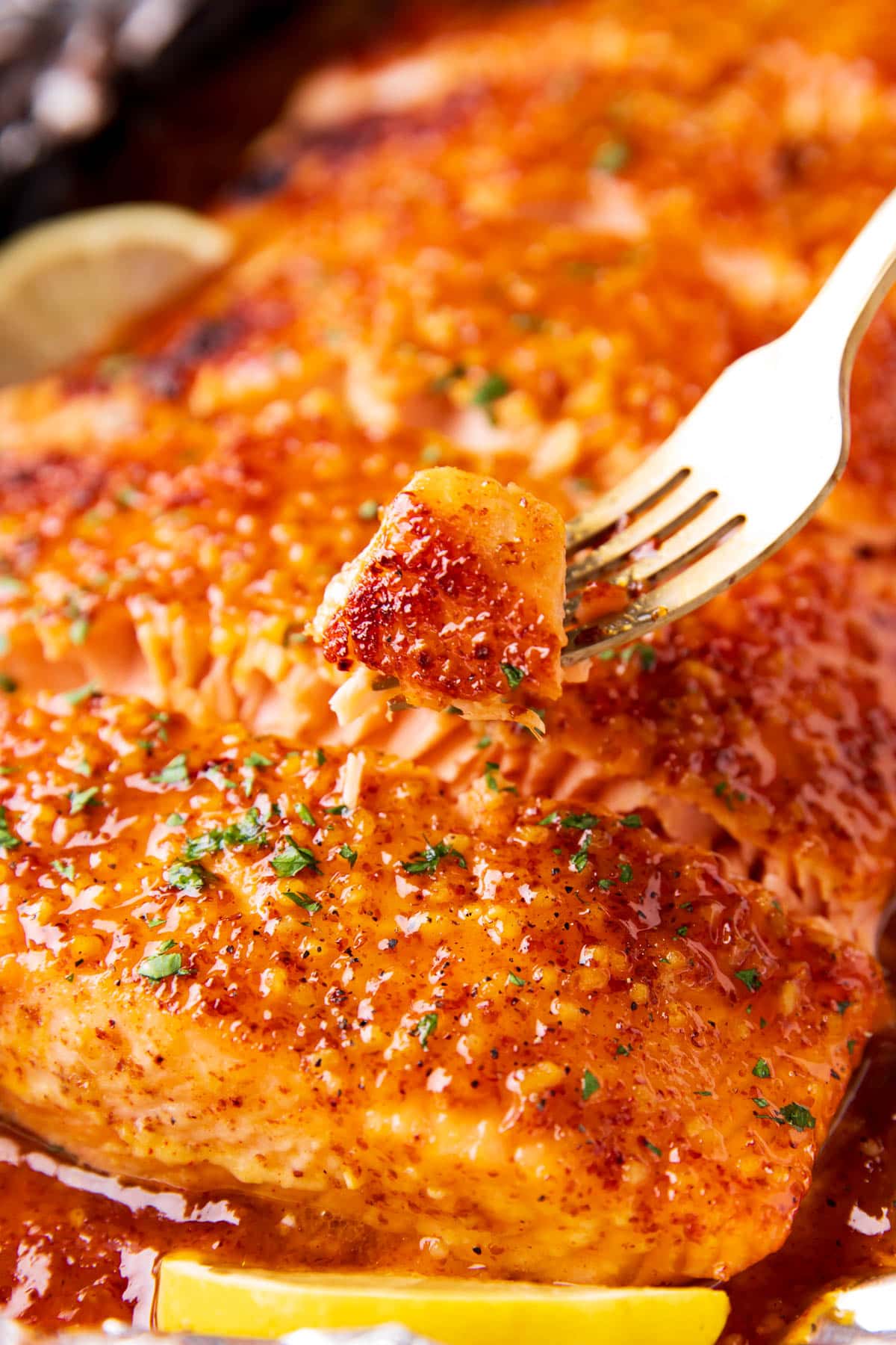 A fork holds up a tender, flaky piece of this sheet pan baked fish recipe.