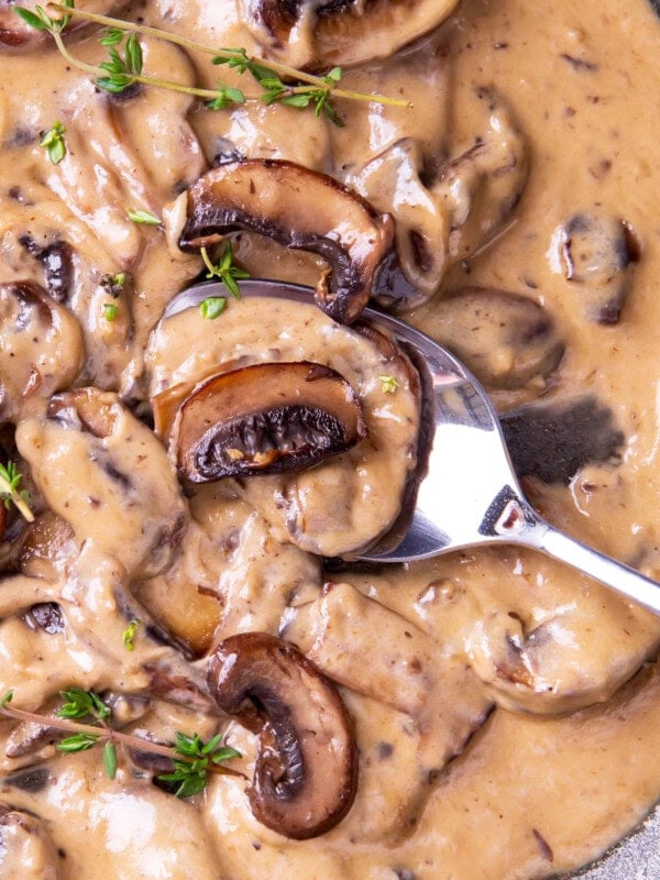 Close up of a spoon filled with Mushroom Sauce to show rich and creamy texture