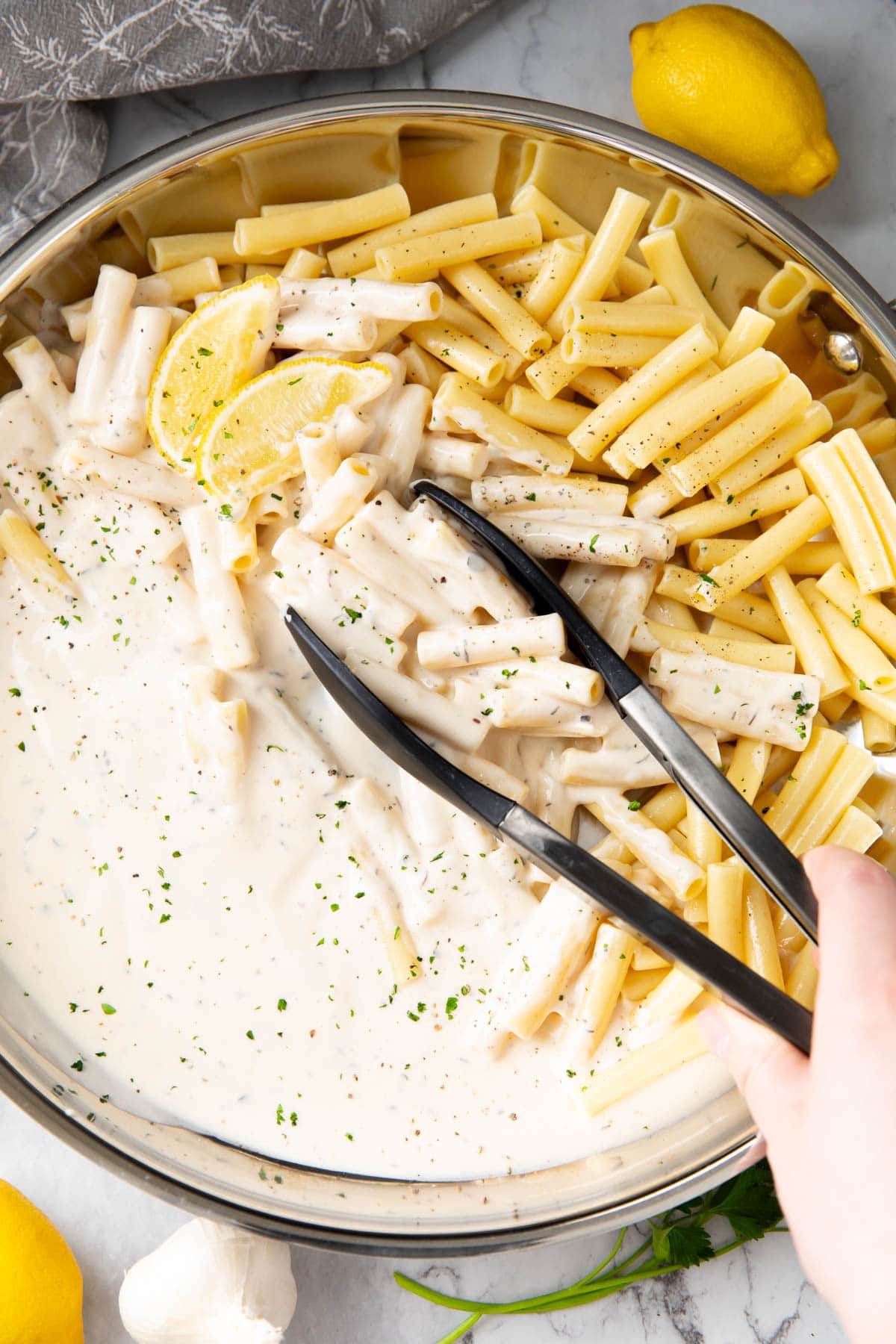 Someone is tossing cooked ziti in this homemade creamy cheese sauce.