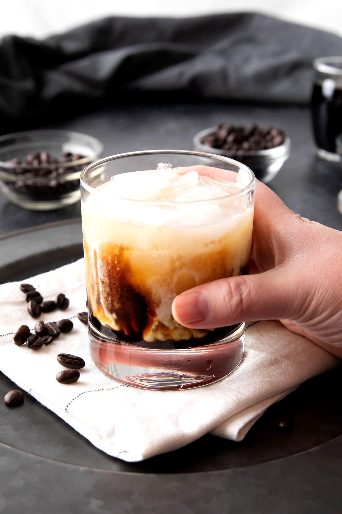 Someone holding a cocktail glass filled with this White Russian drink.