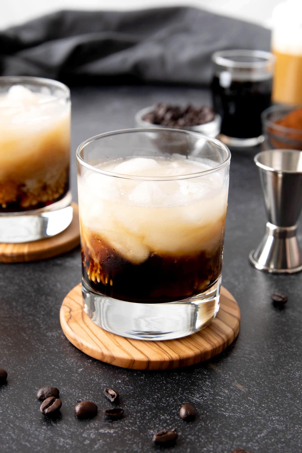 This vodka and Kahlua cocktail drink served on a coaster with coffee beans and milk.