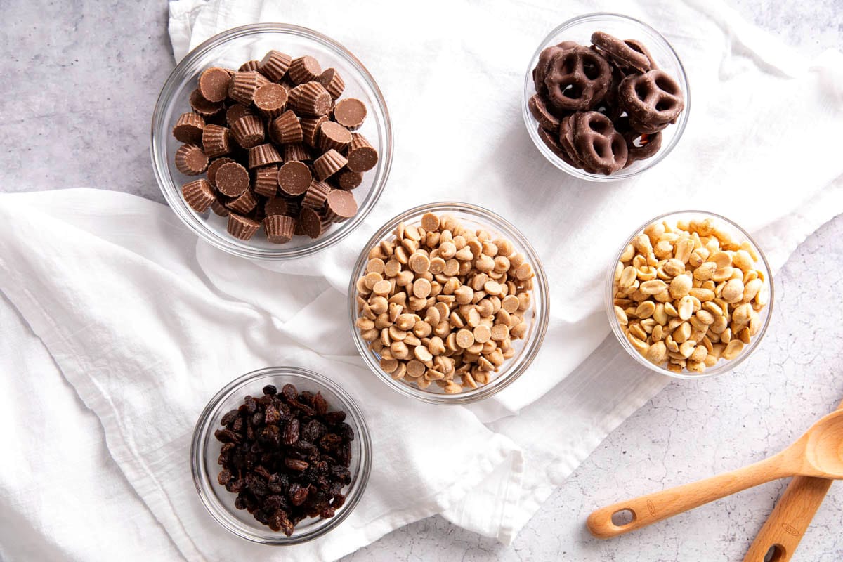 Peanut butter trail mix ingredients includes peanuts, mini peanut butter cups, chocolate covered pretzels, raisins, and peanut butter chips.