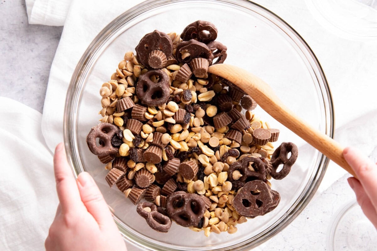 A photo showing How to Make Peanut Butter Trail Mix - someone stirring ingredients together.